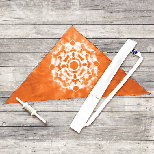Orange tie-dye delta kite with white mandala pattern, shown with hemp string spool and white cotton travel sleeve.